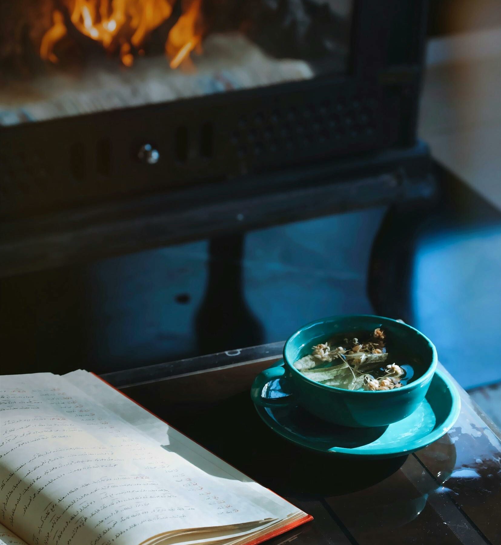 Open journal and herbal tea near a cozy fireplace, symbolizing relaxation, mindfulness, and introspection