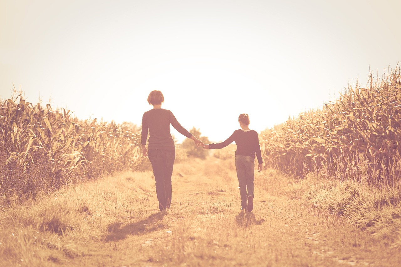 A mother and child walk hand-in-hand down a rural path, symbolizing the connection between childhood upbringing and adult behavior.